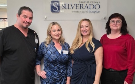 Silverado Coastal Valleys hospice team standing together in front of the Comfort Care branded lobby sign